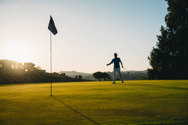 istock A golfer is celebrating a hole at sunset on the green 1805750993