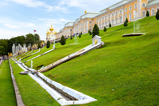 Saint Petersburg, Russia - July 29, 2012: Tourists visiting the Peterhof Palace gardens (built in 18th century) which are a series of palaces and gardens, laid out on the orders of Peter the Great. The palace-ensemble along with the city centre is recognised as a UNESCO World Heritage Site. Upon the bluff's face below the Palace is the Grand Cascade (Bolshoi Kaskad). This and the Grand Palace are the centrepiece of the entire complex.