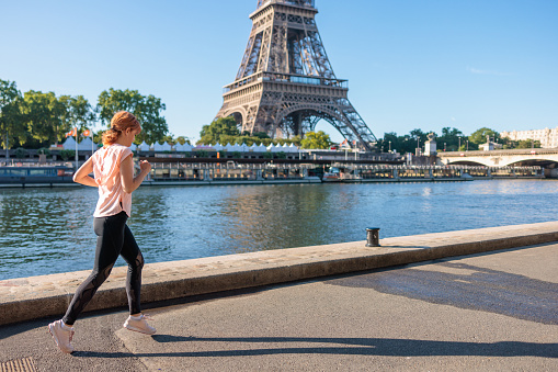 Beautiful mature woman jogging on the promenade by the river Seine in Paris, France, workout on a clear summer day