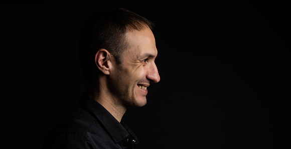 Side view of young man isolated on gray background.