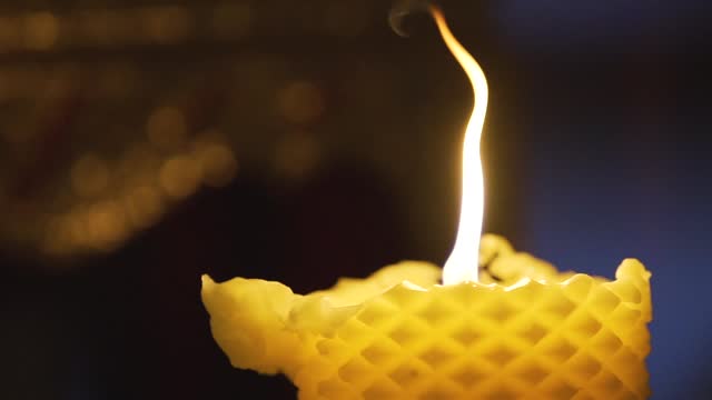 The flame from the Buddhist Lent candle provides light in the darkness during Buddhist Lent
