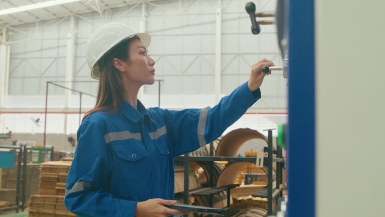 Professional Asian female industrial engineers check machine equipment in manufacturing factory. Working in manufacturing plant or production plant.