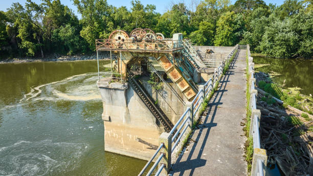 istock Bridge path Maumee River Dam rusting gears and equipment over water choked by trees and swirling basin Fort Wayne, IN aerial 1805791748