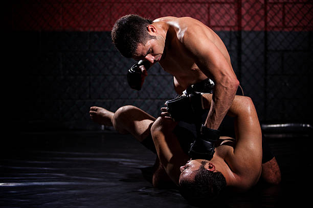 MMA fighter mounting and punching opponent Strong MMA fighter holding his rival down and throwing punches at him during a fight. With plenty of copy space martial arts photos stock pictures, royalty-free photos & images