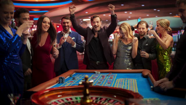 Successful Men and Women Partying in a Luxurious Casino. Young People Gambling at a Roulette Table, Putting High Stakes Bets. Entertainment Industry and Glamorous Lifestyle Concept