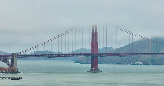 Image of Golden Gate Bridge shrouded in cloudy mist on foggy day aerial over San Francisco Bay, CA