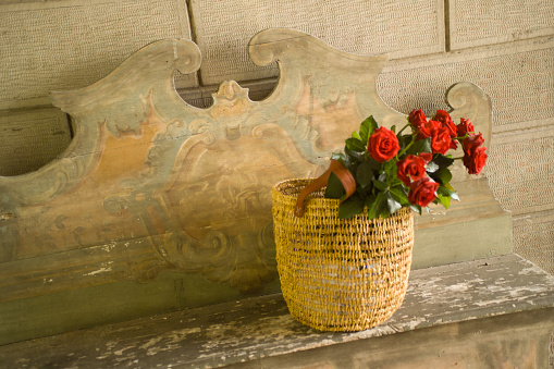 basket with bouquet of roses on wooden bench