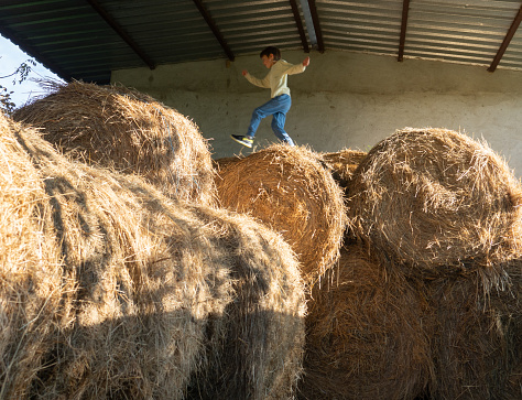 Boy playing on a pile of hay