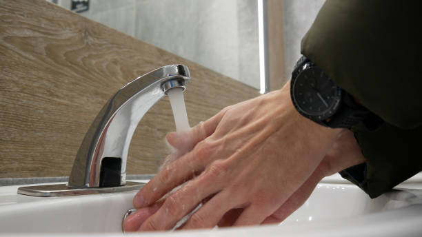 close-up of a faucet in a restroom and a man washing the hands - well fountain water pipe pipe imagens e fotografias de stock