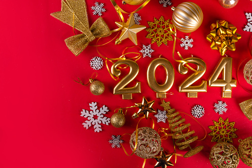 Golden Christmas and New Year baubles, decorations, numbers 2024 on red background, Bright Xmas New Year party invitation, greeting card background top view copy space