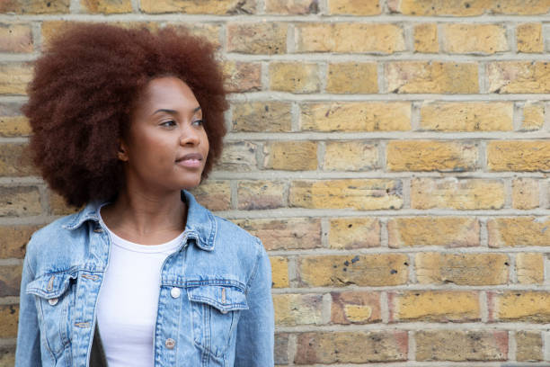 istock Young woman standing by a brick wall with copy space 1805876042