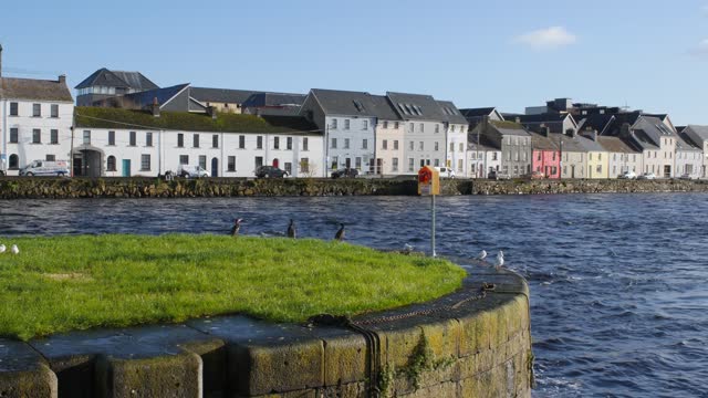 Establishing shot of Galway City center featuring the Long Walk on a sunny day.