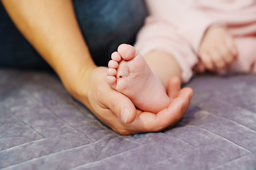 Small children's feet in their parents' hands.