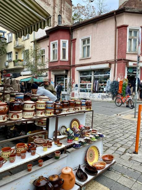 Bulgaria - Sofia - Woman's market We are in this open air market, in front of a stand that sells traditional pots for cooking  of Bulgaria. We can see the stand seller who tidies up his stand11/122023