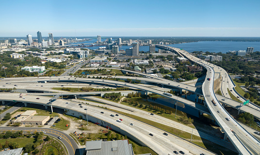 Aerial view of Jacksonville city with high office buildings and american freeway intersection with fast moving cars and trucks. USA transportation infrastructure concept.