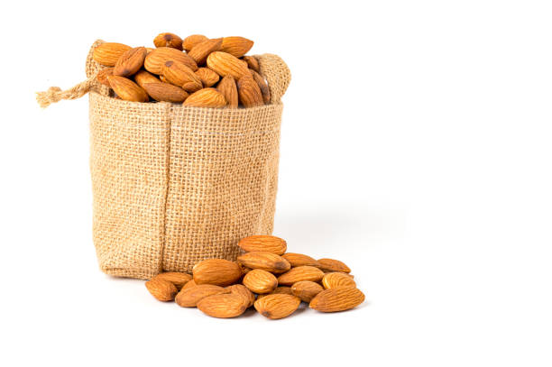 Dried almonds in a sack, dried almonds in a pile on the ground. isolated on white background.