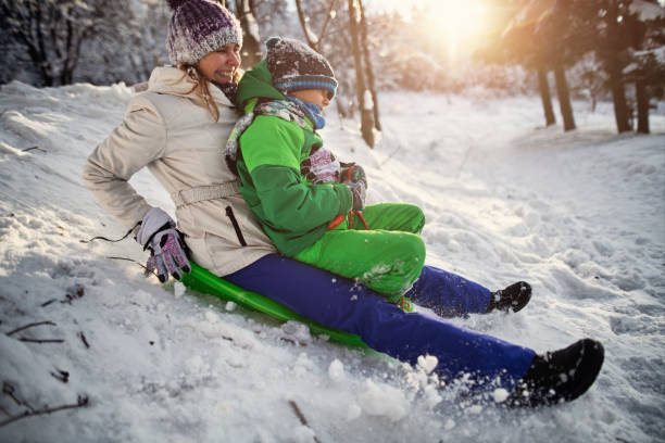 istock Mother and son tobogganing in winter forest 1805949144