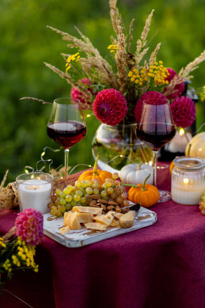 istock Fall mood, romantic date outdoors in the garden, candlelight dinner for a couple. Private wedding for two. Pumpkin countryside decor, red dahlia, cheese plate, grapes. Gourmet food, elegant setting 1805956684