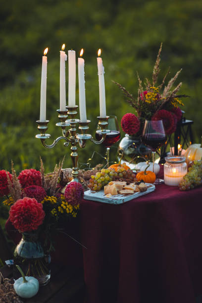 istock Fall mood, romantic date outdoors in the garden, candlelight dinner for a couple. Private wedding for two. Pumpkin countryside decor, red dahlia, cheese plate, grapes. Gourmet food, elegant setting 1805957883