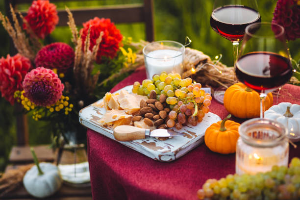 istock Fall mood, romantic date outdoors in the garden, candlelight dinner for a couple. Private wedding for two. Pumpkin countryside decor, red dahlia, cheese plate, grapes. Gourmet food, elegant setting 1805957885