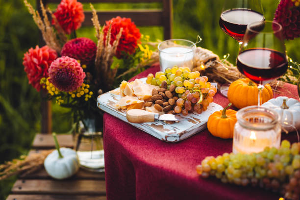 istock Fall mood, romantic date outdoors in the garden, candlelight dinner for a couple. Private wedding for two. Pumpkin countryside decor, red dahlia, cheese plate, grapes. Gourmet food, elegant setting 1805958432