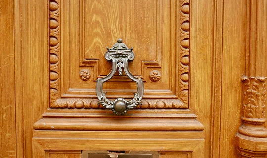 An antique brass door knocker on a painted wooden door.