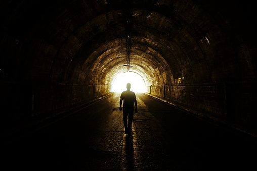 Man walks from darkness to light in the tunnel