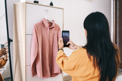 Young woman capturing shirt to sell at online shopping platform