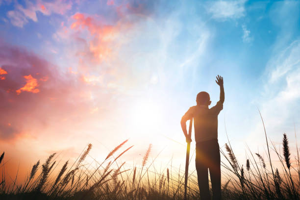 istock a disabled man standing up and raising his hand at sunset background 1805989270