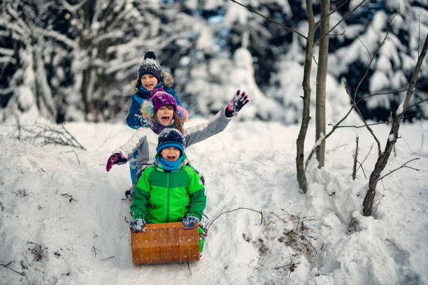 istock Three kids enjoying tobogganing on winter evening. 1805999396