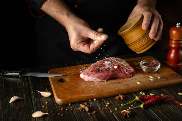 istock The chef sprinkles salt on the raw meat. Preparing beef steak before baking. Working environment in a restaurant or cafe kitchen 1806008855