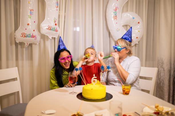 alegre niño caucásico que celebra su 6º cumpleaños con sus madres - ahijado fotografías e imágenes de stock
