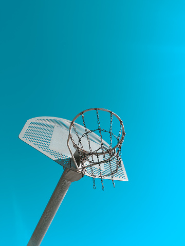Low angle of basketball hoop with net and metallic pole against cloudless blue sky on sports ground on sunny day