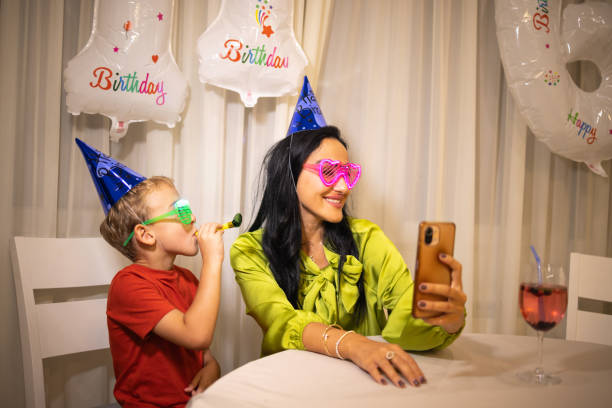 madre tomándose selfie, mientras su hijo celebra su cumpleaños - ahijado fotografías e imágenes de stock