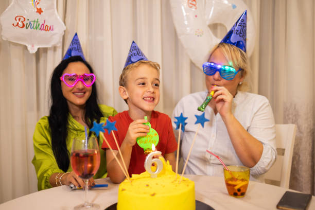 niño caucásico celebrando su 6º cumpleaños con su madre y su niñera - ahijado fotografías e imágenes de stock