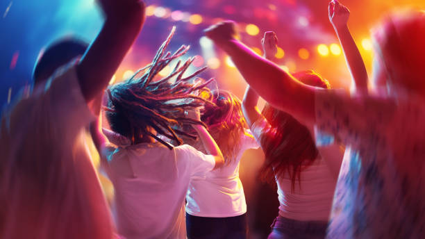Happy, overjoyed people, students dancing raising hand and singing in neon light, spotlights indoor on party in motion blur. Happy, overjoyed people, students dancing raising hand and singing in neon light, spotlights indoor on party in motion blur. Concept of party, festivals, concerts, music and dance, holidays, lifestyle celebrity fans stock pictures, royalty-free photos & images