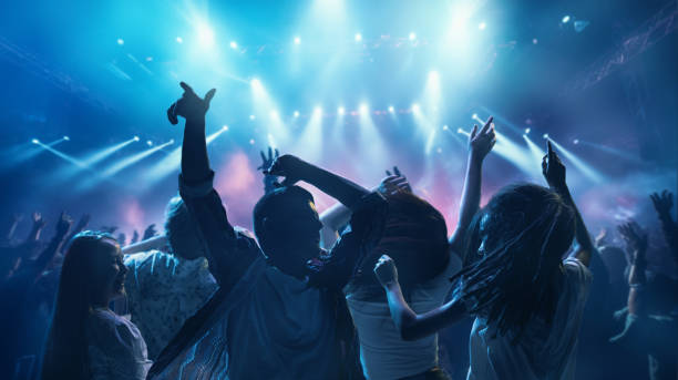 Happy, overjoyed people, students dancing raising hand and singing in neon light, spotlights indoor on party. Happy, overjoyed people, students dancing raising hand and singing in neon light, spotlights indoor on party. Concept of party, festivals, concerts, music and dance, holidays, lifestyle, event. celebrity fans stock pictures, royalty-free photos & images