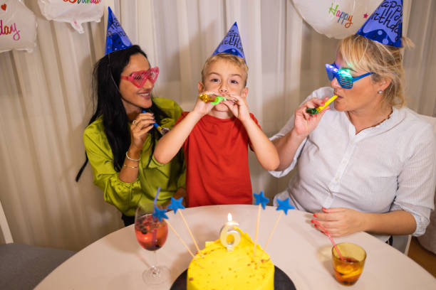 niño caucásico emocionado celebrando su 6º cumpleaños con sus madres - ahijado fotografías e imágenes de stock