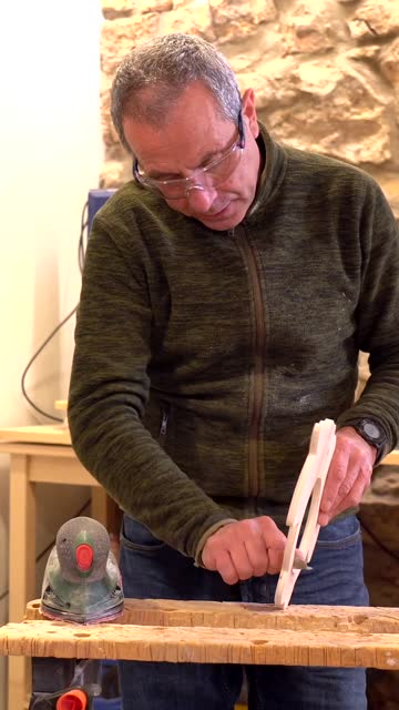 Carpenter using an electric tool to polish a piece of wood in studio workshop