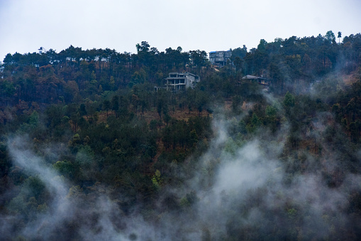 A house in Meghalaya at hill top with clouds floating below it .