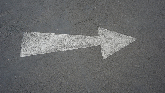 Hand drawn of a white arrow on the asphalt.