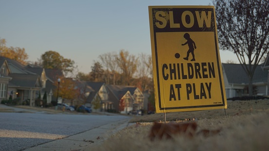 A street sign is displayed at a curb in front of a child's playground, providing safety and guidance for the young ones