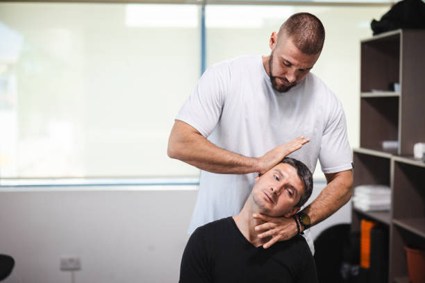 jeune chiropraticien travaillant avec son client - physical therapy back table patient photos et images de collection