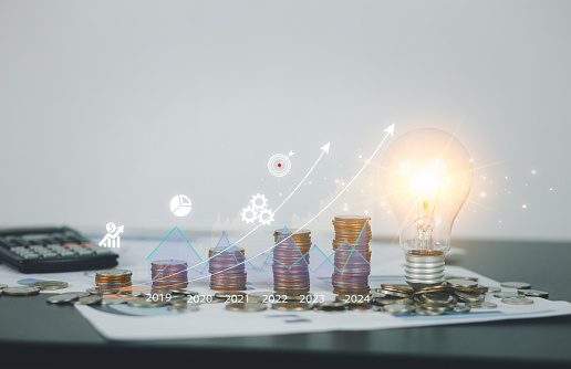 Stack of coins with glowing light bulbs and candlestick chart market chart Innovation financial development and investment grow, crypto to the development of e-commerce management for future success.