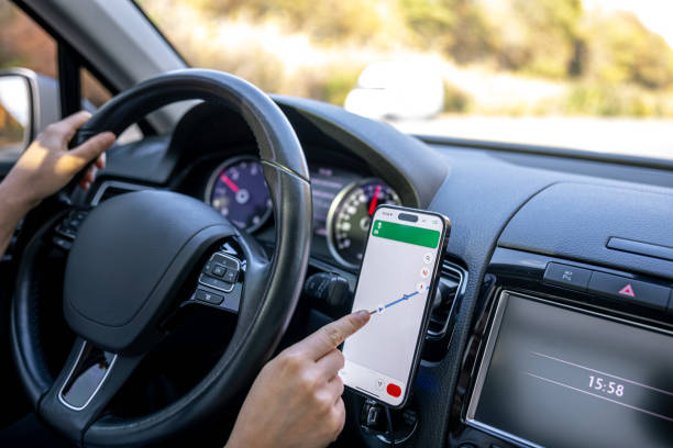 istock A woman in a car holds a mobile phone with a GPS navigation map. 1806116652