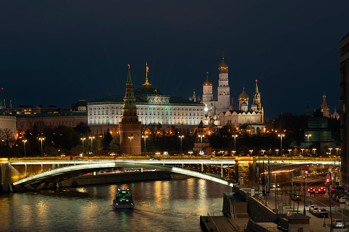 View of the building of the Grand Kremlin Palace, the Annunciation Tower and the ensemble of the Kremlin Cathedral Square from the embankment of the Moskva River with night lighting, Moscow, Russia