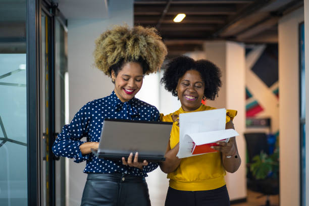 afro friends walk through the office checking their laptop - flowchart marketing diagram women imagens e fotografias de stock