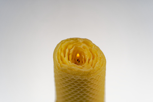 Close-up of yellow beeswax candle against white background. Photo taken November 21st, 2023, Zurich, Switzerland.