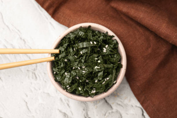 istock Chopped nori sheets with sesame and chopsticks on white textured table, flat lay 1806139760