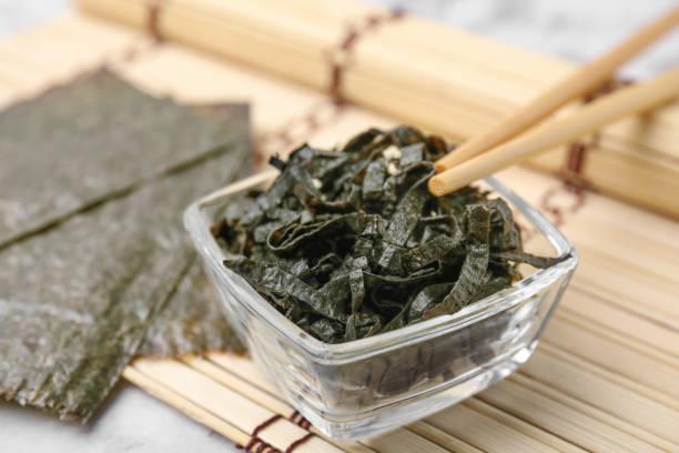 istock Chopped nori sheets with sesame and chopsticks on white table, closeup 1806140276
